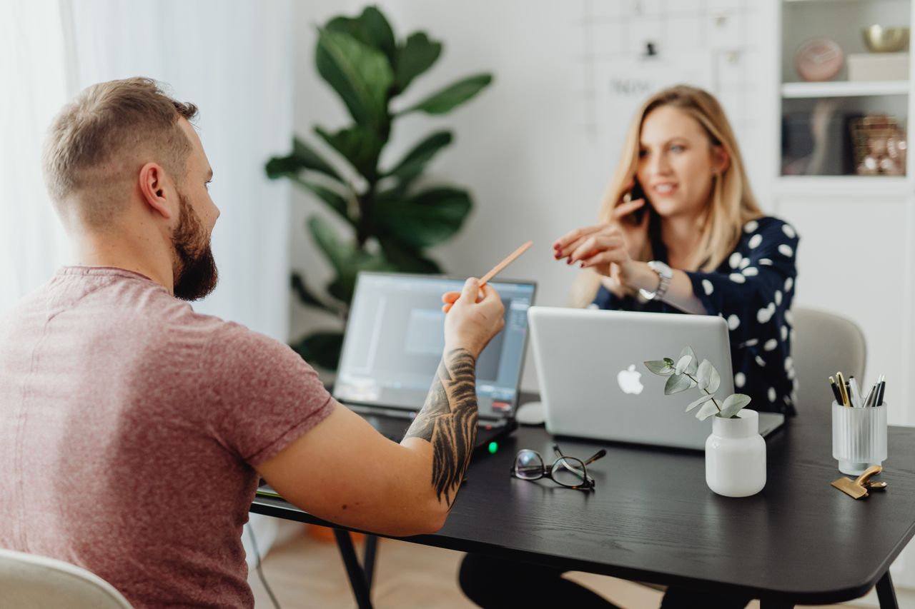 Crafting Captivating Headlines: Your awesome post title goes here Man and woman discussing work at a table with laptops in a modern office.